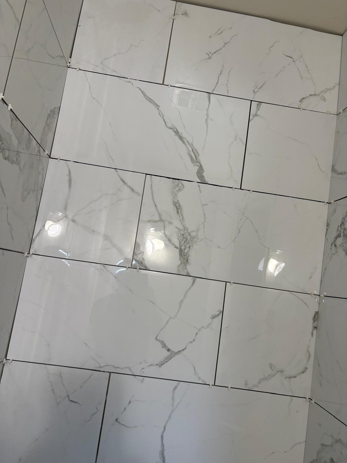 Large-format marble-look porcelain wall tiles being installed with spacers