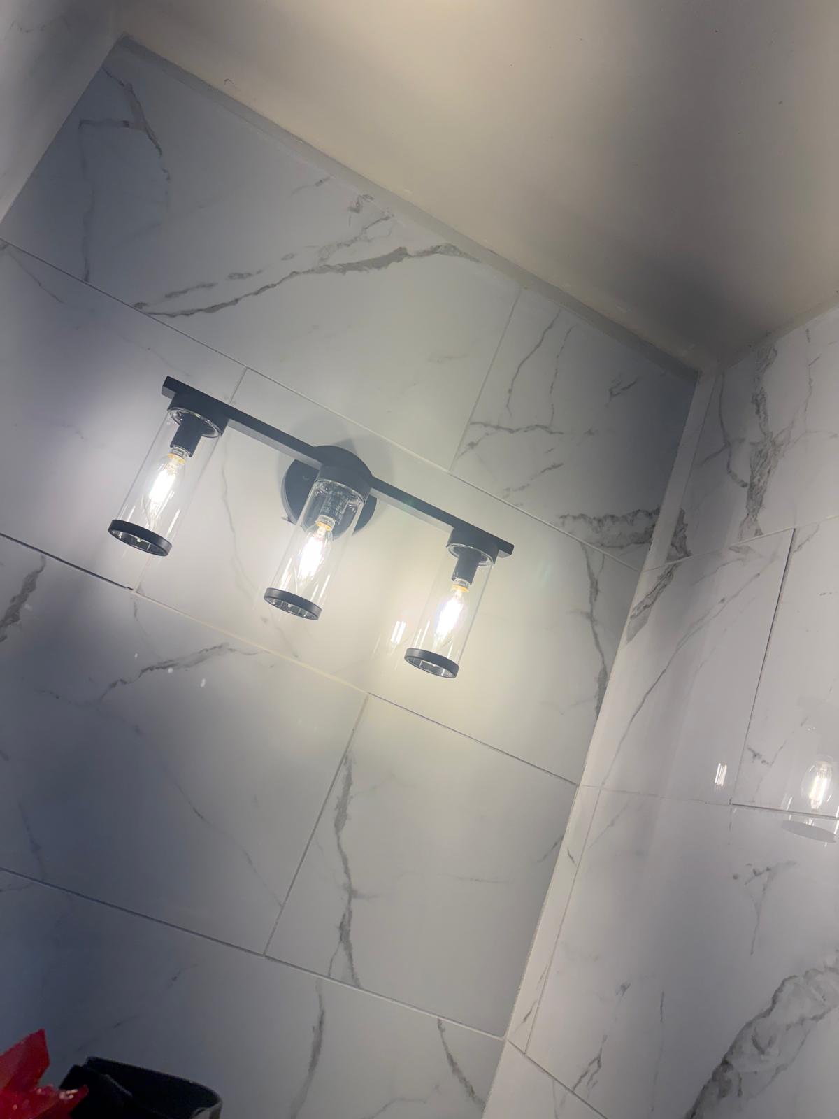 Bathroom remodel with marble-look wall tile and vanity light fixture