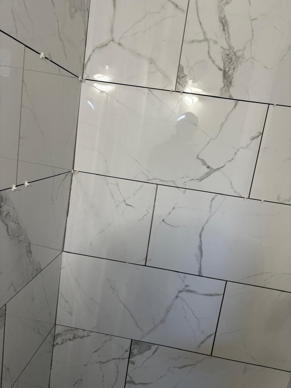 Marble-look wall tile installation with spacers in place
